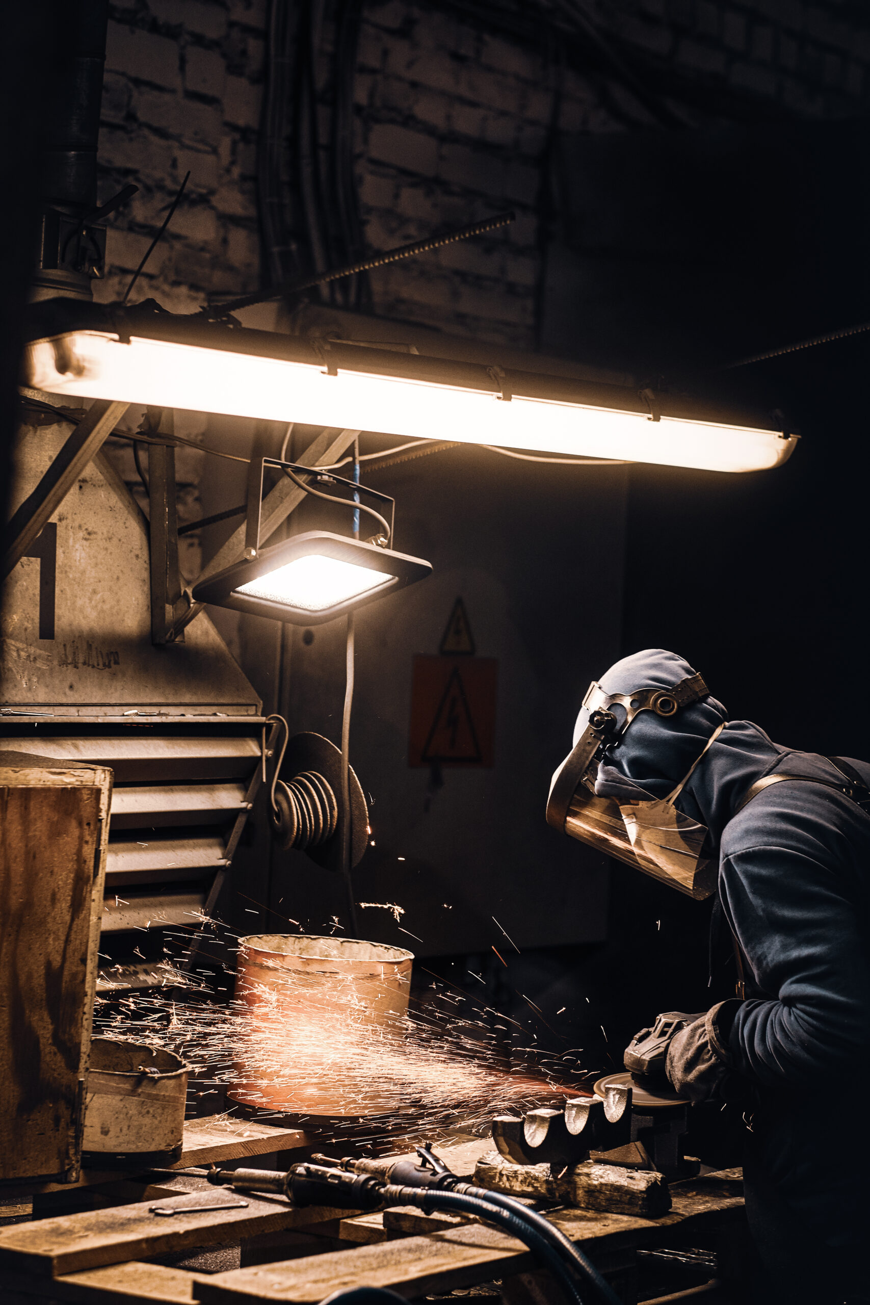 Man in protective mask is cutting metal and sparks are flying away.